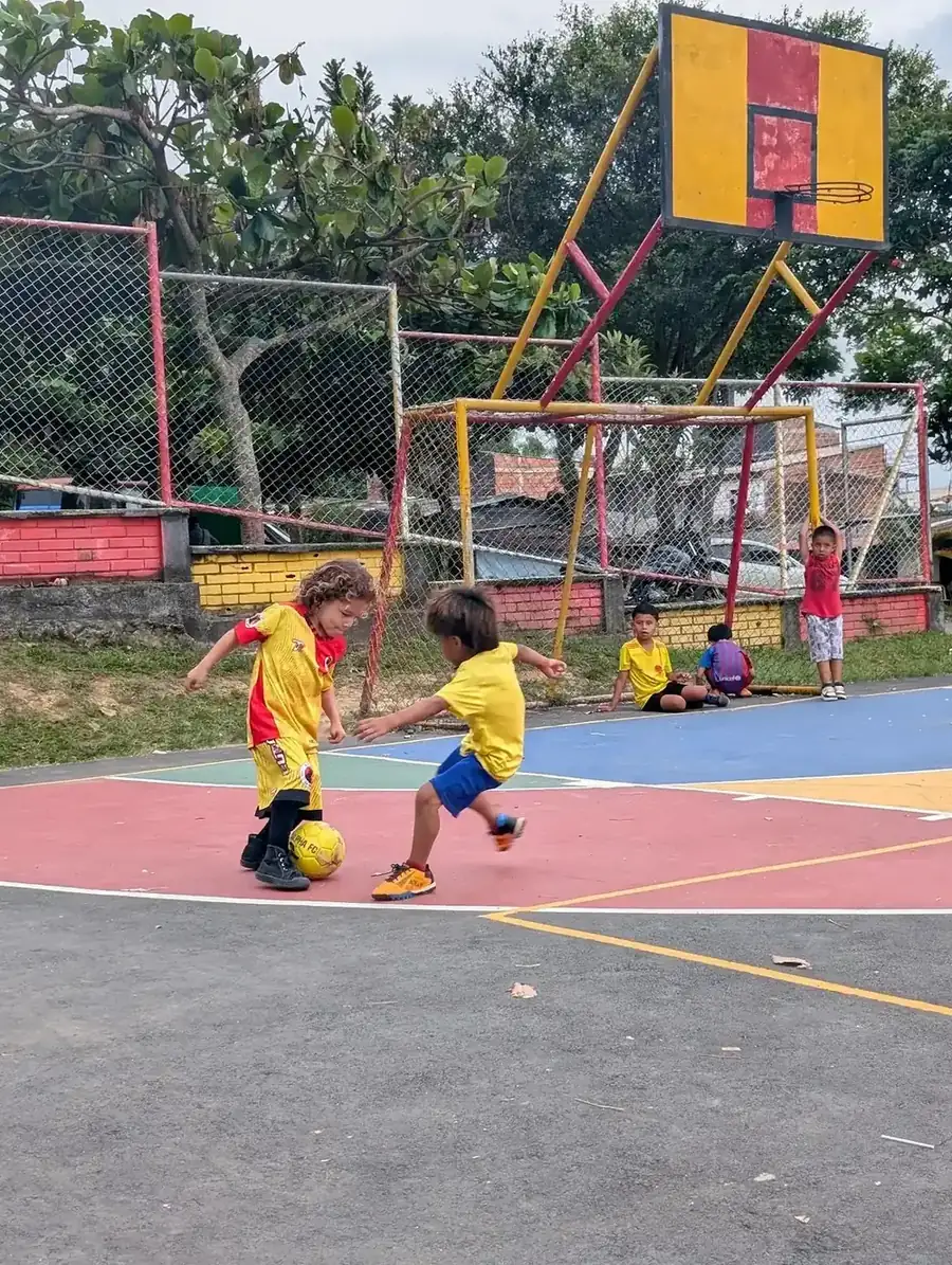 Two young Alpha FC players practicing fútbol sala together on a community court in Pereira