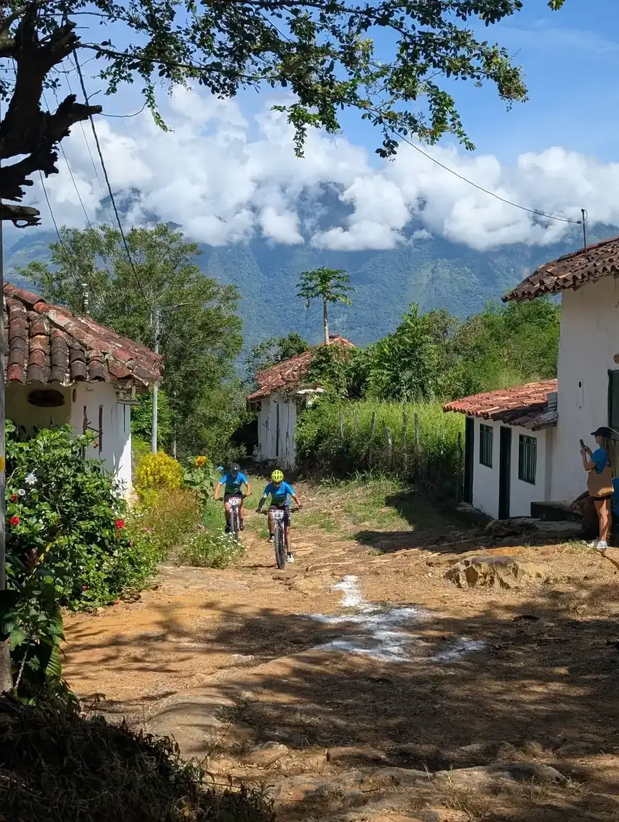 Two Pedalea con Conciencia riders cycling through a rural neighborhood near Cabrera