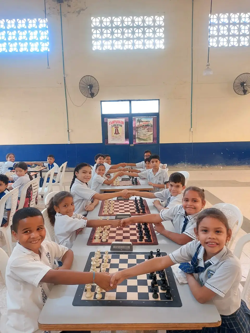 Estudiantes sonríen juntos alrededor de tableros durante una sesión escolar en Santa Marta
